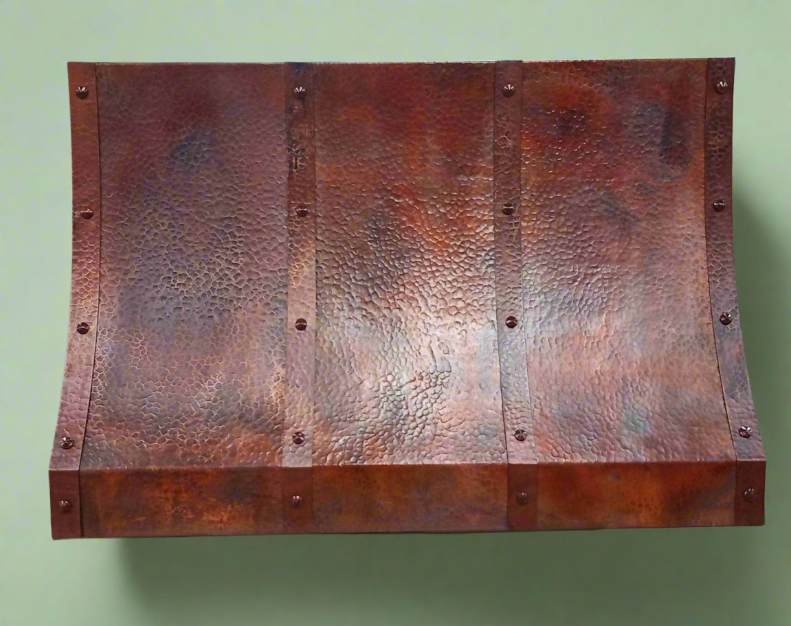 Elegant kitchen featuring a handcrafted hammered copper range hood by Amoretti Brothers, demonstrating the blend of luxurious design and modern functionality in a stylish setting.