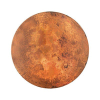 Top view of a round hammered copper table with a naturally weathered and patinated surface, displaying a rich, varied texture in shades of orange and brown