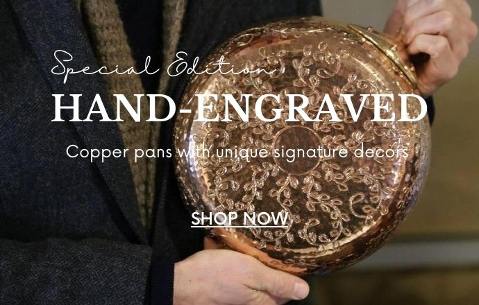 A hand-engraved copper pan, showcasing intricate and delicate designs etched into its surface. The rich, warm tones of the copper highlight the detailed craftsmanship and artistry, making the pan not only a functional cooking tool but also a stunning decorative piece. The engraved patterns add a unique and personal touch, perfect for any kitchen or display.
