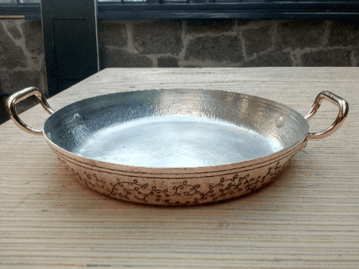 Artisan 13-inch copper paella pan featuring intricate engravings, durable dual handles, and a tin-lined interior for perfect cooking results.