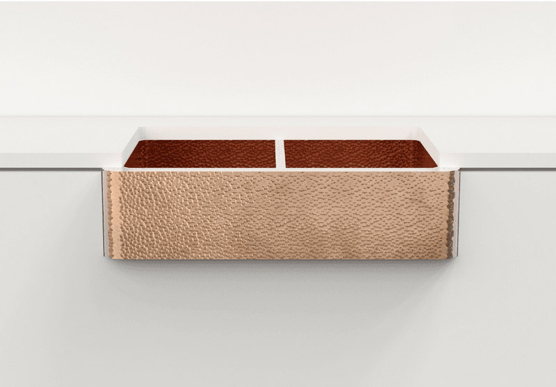 Double-bowl hammered copper kitchen sink with an apron, showcasing its elegant design and artisanal craftsmanship.