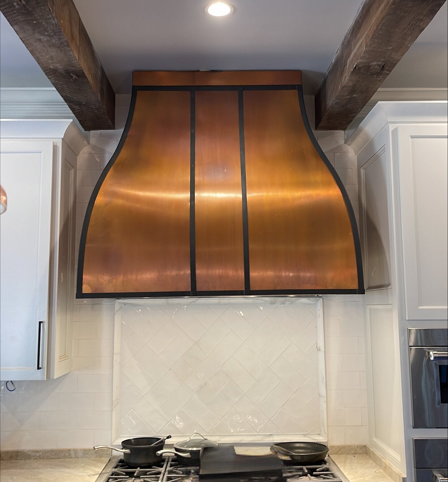 handcrafted copper range hood with black stripes