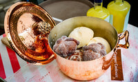 Amoretti Brothers decorative copper dutch oven with cookies on a table
