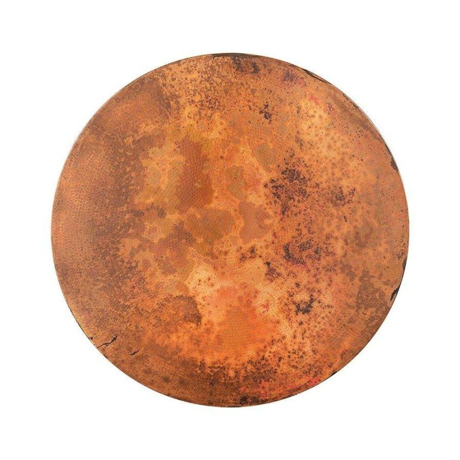 Top view of a round hammered copper table with a naturally weathered and patinated surface, displaying a rich, varied texture in shades of orange and brown