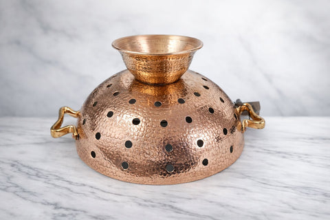 Amoretti Brothers copper colander with perforated design on a marble surface