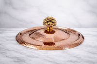 Copper lid with a decorative knob on a marble surface