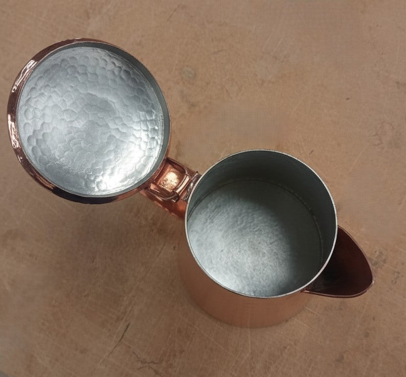 Copper teapot with textured interior on a beige surface