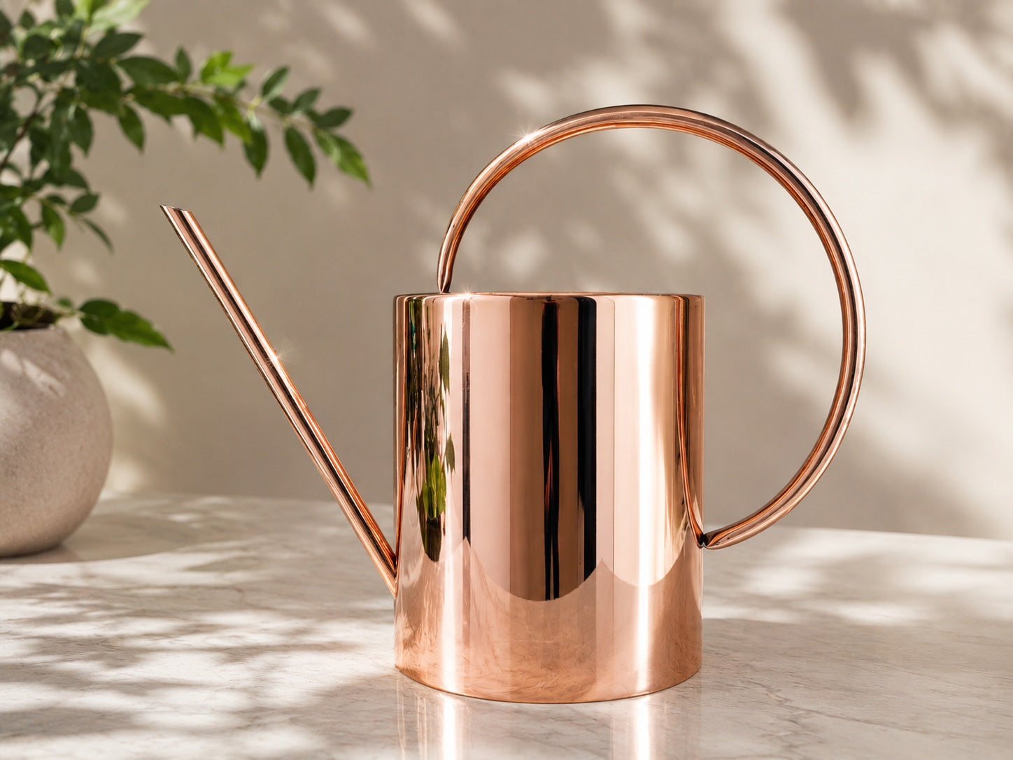 Amoretti Brothers copper watering can on a marble surface with a plant in the background