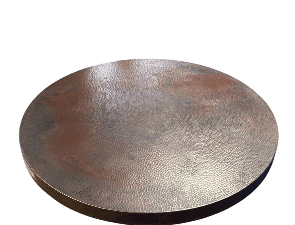 Hand-hammered copper table top glowing in natural light, highlighting its warm, rich tones and textured surface