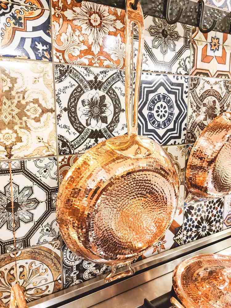 copper fry pan or skillet by amoretti brothers on a tiles wall