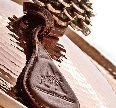 Detailed close-up of the flower-shaped lid on a 10-quart hammered copper stock pot, highlighting intricate design.